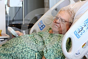 Elderly male hospital patient holds TV remote