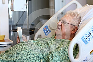 Elderly male hospital patient holds TV remote