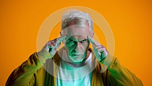 Elderly male mentalist demonstrating mind-reading power at camera, telepathy