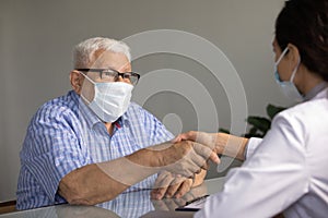 Elderly male patient in facemask handshake doctor