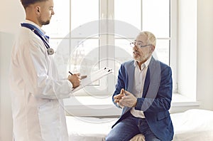 Elderly Male Patient Talking To Doctor In Hospital Office