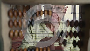 Elderly male person in glasses calculating with vintage wooden abacus.