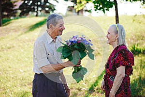 An elderly man of 80 years old gives flowers to his wife