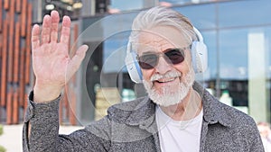 Elderly man in advanced headphones waving his hand outside