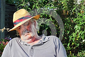 Elderly man asleep wearing hat.