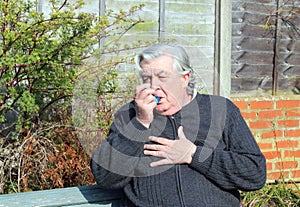 Elderly or old man with asthma inhaler. photo