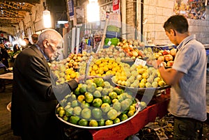 Elderly man buying the lemons and other juicy fruits on the asian street market.