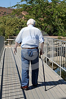 Elderly man with a cane walks away photo