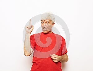 elderly man in casual striped shirt pointing index finger aside up on mock up copy space