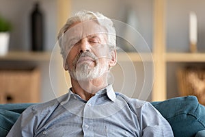 Elderly man closed eyes leaned on sofa having day nap