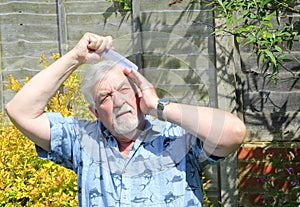 Elderly man combing his hair.