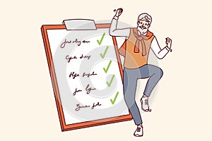 Elderly man completed all tasks and dancing near giant clipboard with list of goals and checkmarks