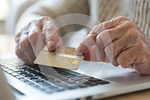 Elderly man with credit card making online purchases on laptop