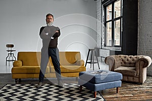Elderly man with crossed arms in spacious flat