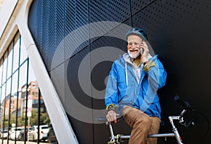 Elderly man, cyclist traveling through the city by bike. Senior city commuter making phone call