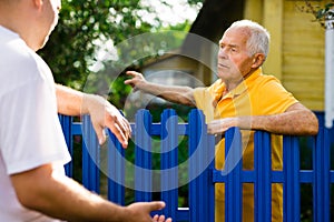 Elderly man discussing with neighbour beside house