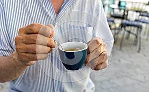 Elderly man drinking espresso coffee at an outdoor cafe