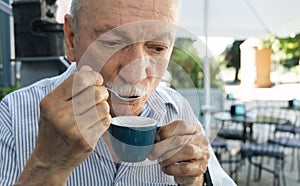 Elderly man drinking espresso coffee at an outdoor cafe