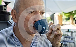 Elderly man drinking espresso coffee at an outdoor cafe