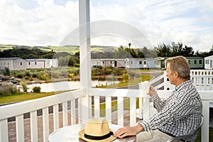 Elderly man drinking a mug of coffee sitting on the veranda of a