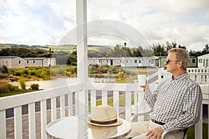 Elderly man drinking a mug of coffee sitting on the veranda of a