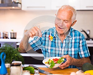 elderly man eating fresh vegetable salad at home