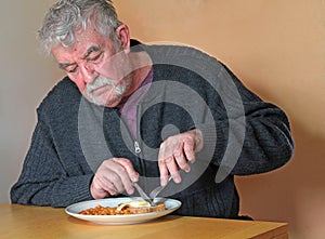 Elderly man eating at a table.