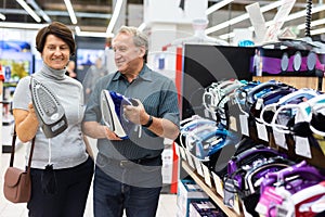 Elderly man and elderly woman choose iron in store