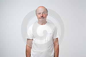 Elderly man emotions, portrait of serious senior caucasian man looking at camera against gray wall