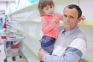 Elderly man at empty shelves in shop with child