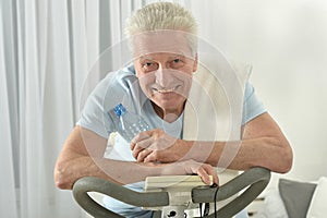 An elderly man is exercising on an exercise bike