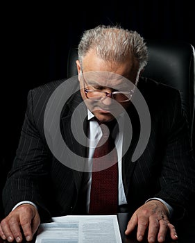 The elderly man in eyeglases reads the document photo