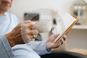 elderly man in eyeglasses sitting at home on the sofa reading a book