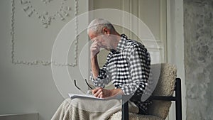 An elderly man falls asleep while sitting while reading. Aging and dementia.