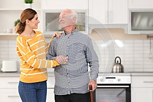 Elderly man with female caregiver in kitchen.