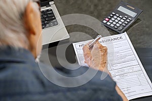 Elderly man filling health insurance form