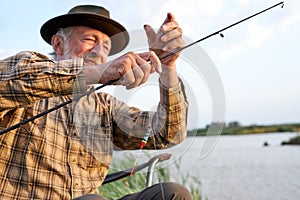 Elderly man fishing on lake. Fish on hook. Master baiter. Gone fishing. Summer vacation.