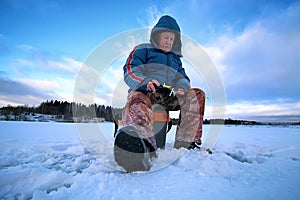 Elderly man fishing in the winter on the lake