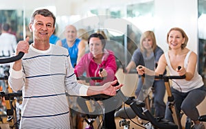 Elderly man on fitness cycle in fitness club