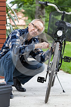 Elderly man fixing bicycle