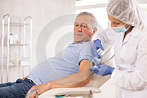 Elderly man getting intramuscular injection in upper arm in medical office