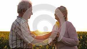 Elderly Man Gives Woman Flower Standing In Rural Field At Sunset