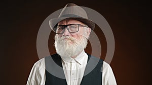 Elderly man in glasses firmly disapproving with a stern nod