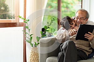 Elderly man with granddaughter using tablet together