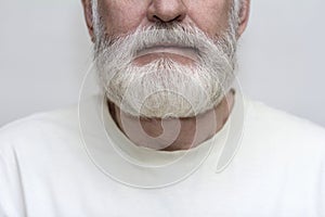elderly man with a gray beard holds his throat with his hands