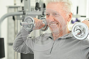 Elderly man in a gym with dumbbells