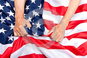 Elderly man hands compresses a USA flag. The concept of caring f