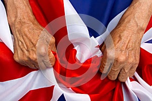 Elderly man hands holding a UK flag. The concept of caring for p