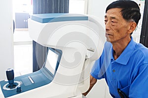 Elderly man having hes eyes examined by an eye doctor on a testing tool in modern clinic