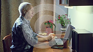 Elderly man having video chat making video call on webcam using a laptop and headphones at home